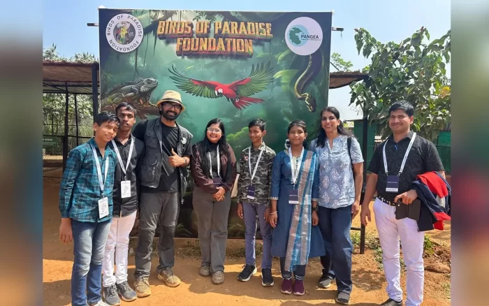 A few people pose in front of the Birds of Paradise Foundation Banner on location
