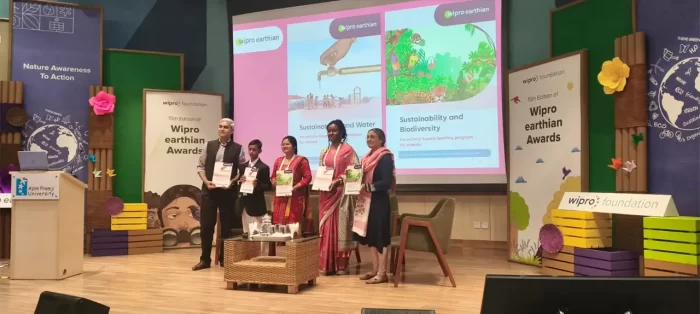 BVE team stands on stage with the booklet for the launch of the Accessible Earthian Biodiversity and Water Booklets for visually impaired students