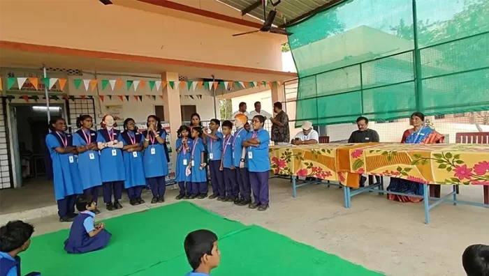 Students are performing or participating in a group activity on a decorated stage.
Teachers and staff are present, guiding and supporting the students.
The image highlights confidence, expression, and inclusive participation.