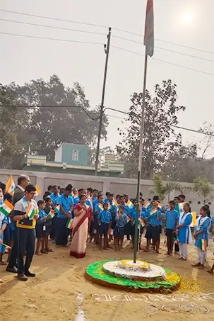 Students and teachers are assembled around a flag during a school celebration.
The gathering reflects collective participation and national pride.
The image captures a moment of shared respect and unity.
