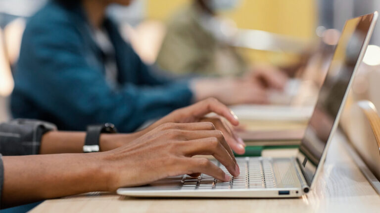 A young man's hands typing on a keyboard.