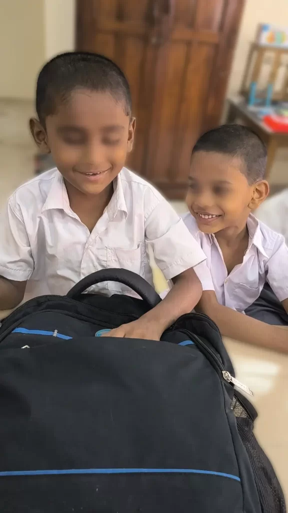 A child with visual impairment is played, fully checking out the contents of a bag. His friend watches on.