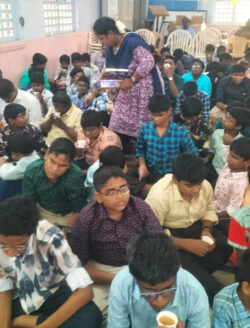 This image is of a teacher from Tirunelveli school, who is distributing chocolates on Children’s Day on behalf of VE, while the kids are seated below for a celebration