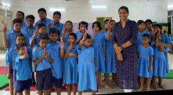 This image is of students of OAB School, standing for a picture posing with chocolates in their hand with their teacher, distributed by VE on the occasion of Children’s Day celebrations