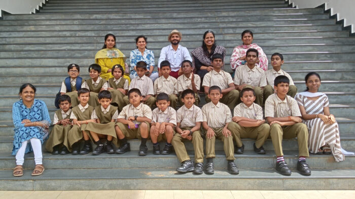Students and teachers from JSB Blind School, along with VE facilitators, are seated on the staircase at the ARC for a group photo during their visit.