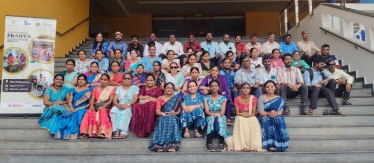 A group image of teachers who were a part of the Pragya Training session in Karnataka, sitting together on the staircase of the entrance of IIIT Bangalore