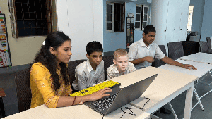 teacher explaining to 3 students from a laptop in front of her