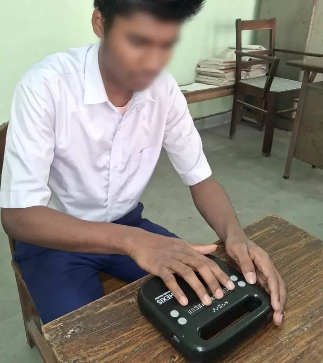 Subhastryan using a Hexis Braille Reader to read